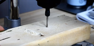 a drill press drilling holes into a piece of wood