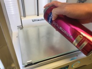 Applying hairspray to build plate of 3D printer